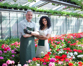 Twee kwekers in een kas met bloemen, met de juiste pbm