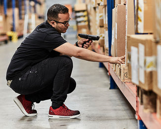 Een magaizjn medewerkers aan eht scannen, op de Rode Redbrick Motion Spirit S1P veiligheidsschoenen